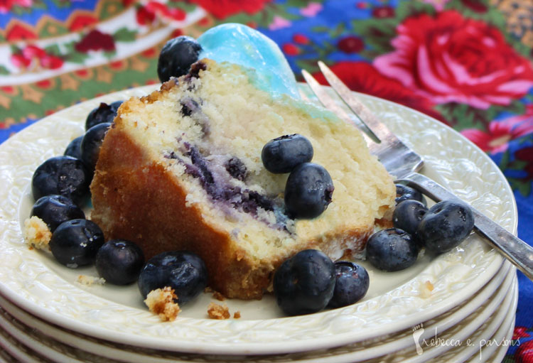A slice of Gluten Free Blueberry Orange Cake topped with fresh blueberries.