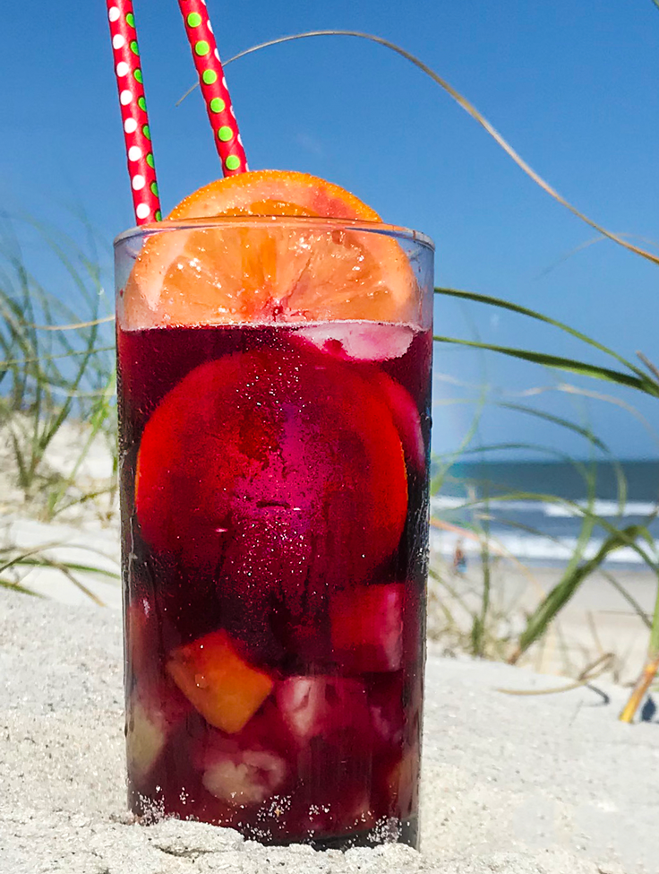 tall glass of sangria with ocean in the background